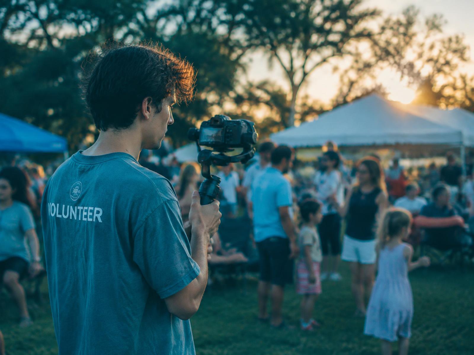 A volunteer filming a community church picnic